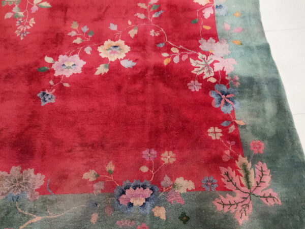 Red and green rug with a plush texture and scattered pastel floral motifs.