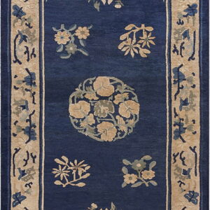 Navy blue rug with a wide tan border and stylized gold and sage floral patterns throughout the field.