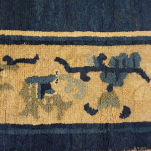 Textured rug border featuring navy and gold bands with stylized floral designs in blue and slate.