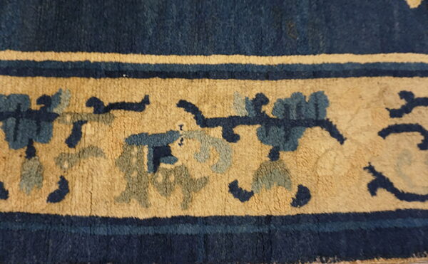 Textured rug border featuring navy and gold bands with stylized floral designs in blue and slate.
