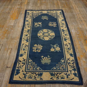 A narrow blue rug with cream and green floral patterns rests on distressed wooden floors.