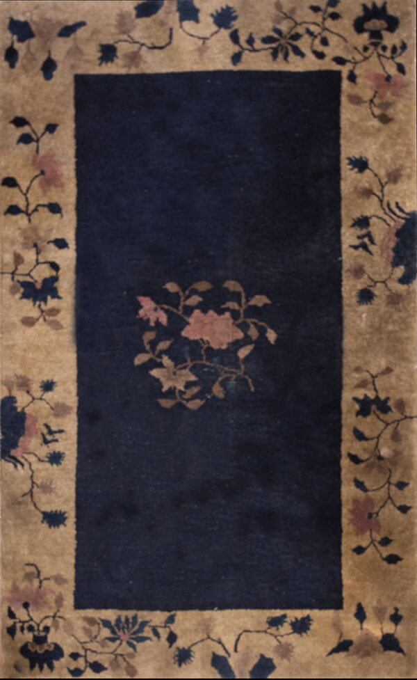 Rectangular rug with a dark blue field and a wide beige border patterned with scrolling pink and navy flowers.