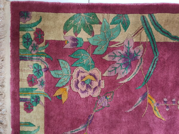 Plush magenta rug featuring a flowing floral pattern in beige, teal, purple, and pink, with visible fringe.
