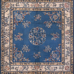 Deep blue rug with an ornate cream and tan floral border framing a blue field with complementary flower motifs.
