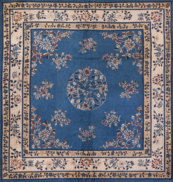 Deep blue rug with an ornate cream and tan floral border framing a blue field with complementary flower motifs.