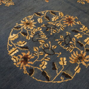 Detailed view of a deep blue rug showing a gold and brown floral medallion pattern.