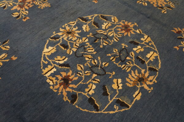 Detailed view of a deep blue rug showing a gold and brown floral medallion pattern.