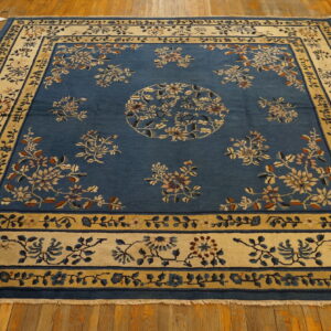 Blue area rug featuring a central medallion and detailed floral borders resting on a polished hardwood floor.