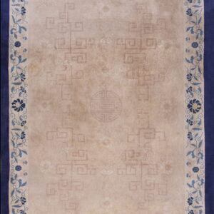 Low-pile beige rug with subtle patterns and a blue floral border framed by a wide navy edge.
