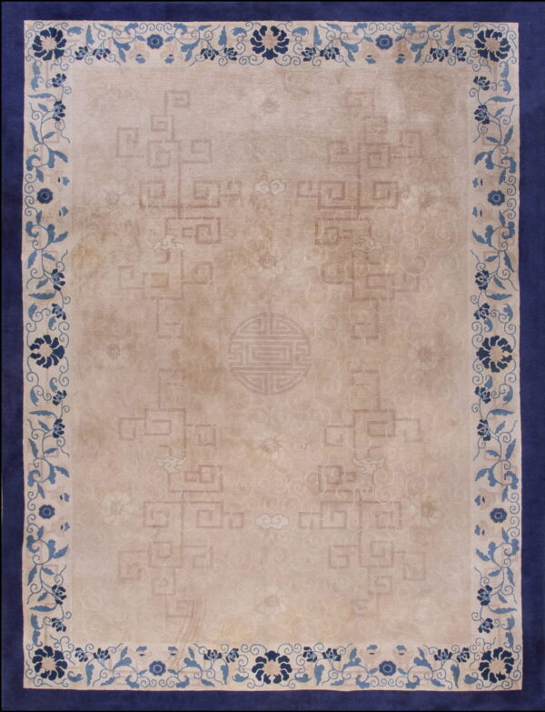 Low-pile beige rug with subtle patterns and a blue floral border framed by a wide navy edge.