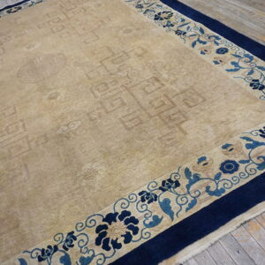 A beige rug with subtle patterns and a blue floral border rests on distressed wooden floorboards.