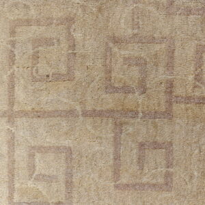 Tan high-pile rug detail showing a distressed pattern of light brown interlocking geometric borders.
