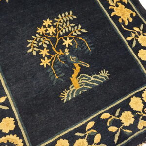 Navy rug featuring a central gold and sage green tree motif with wide ornate floral borders.