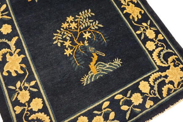 Navy rug featuring a central gold and sage green tree motif with wide ornate floral borders.