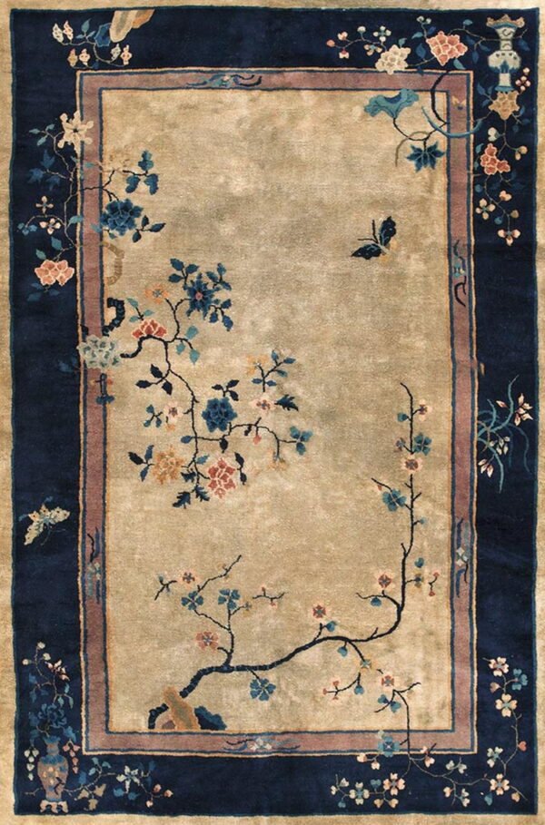A beige rug with a wide navy blue border features delicate flowering vines and butterflies.