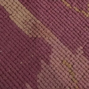Textured, low-pile rug close-up featuring diagonal stripes in shades of deep purple and light tan.
