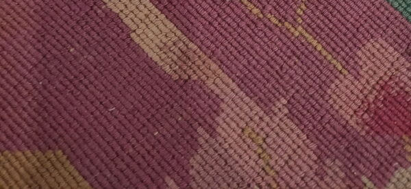 Textured, low-pile rug close-up featuring diagonal stripes in shades of deep purple and light tan.