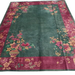Deep green rug featuring a wide magenta border with pink and yellow floral designs.