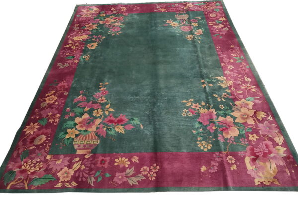 Deep green rug featuring a wide magenta border with pink and yellow floral designs.