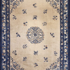 Beige rug with navy borders and detailed blue and tan floral patterns across the field.