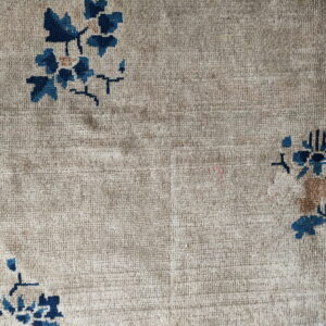 Textured beige rug detail with scattered deep blue and light brown floral designs.