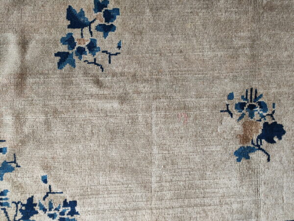 Textured beige rug detail with scattered deep blue and light brown floral designs.