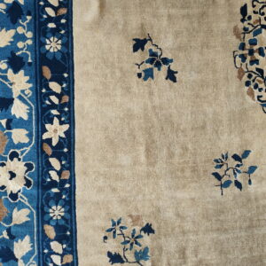 Beige field rug with large navy and light blue floral border and scattered medallions.