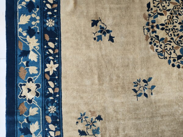 Beige field rug with large navy and light blue floral border and scattered medallions.
