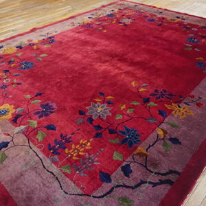 Deep red rug with a purple border and colorful floral pattern on distressed wood flooring.