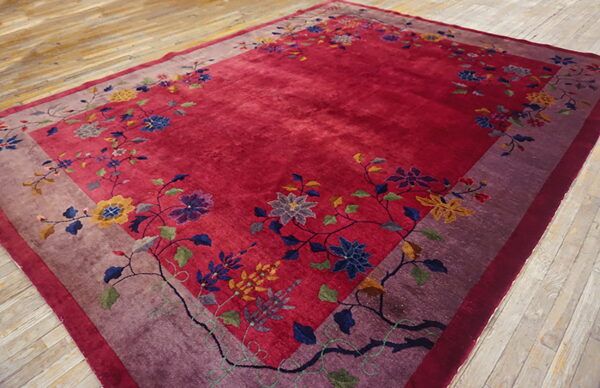 Deep red rug with a purple border and colorful floral pattern on distressed wood flooring.