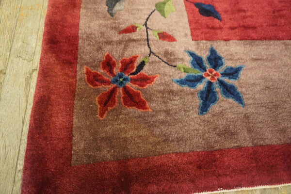 High-pile floral rug with red and blue flowers on a brown field next to light wood flooring.