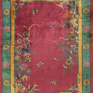 Fuchsia rug field with intricate multicolored floral sprays, framed by gold and teal green patterned borders.