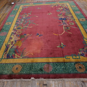 Red field rug featuring floral and butterfly designs, framed by mustard yellow and green decorative borders.
