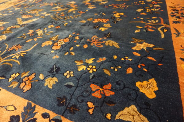 Plush blue rug featuring ornate gold and orange floral patterns and a wide contrasting orange border.