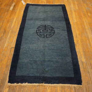 Low-pile blue runner rug featuring a dark navy border and central medallion on worn hardwood planks.