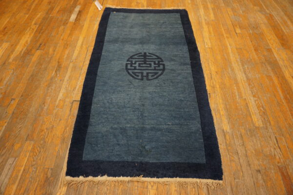Low-pile blue runner rug featuring a dark navy border and central medallion on worn hardwood planks.