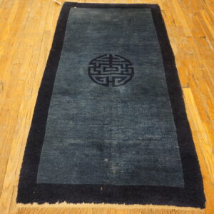 Dark blue runner rug with a thick navy border and central symbol laid on a honey-toned wood floor.