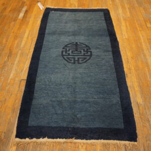 A blue rug runner with a dark navy medallion and border on a distressed wood floor.