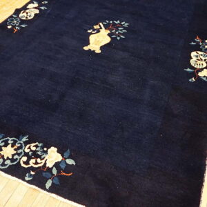 Navy rug with pale yellow vase and scattered blue floral corner designs over light wooden planks.