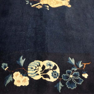 Plush, dark blue rug featuring a border detail of cream and teal stylized floral designs.