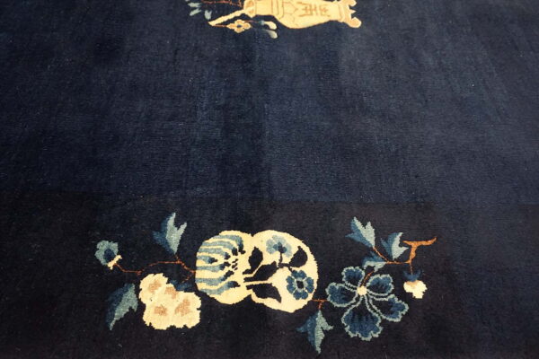 Plush, dark blue rug featuring a border detail of cream and teal stylized floral designs.