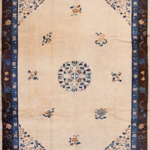 Large cream rug featuring detailed blue and brown floral borders over honey-toned wood flooring.