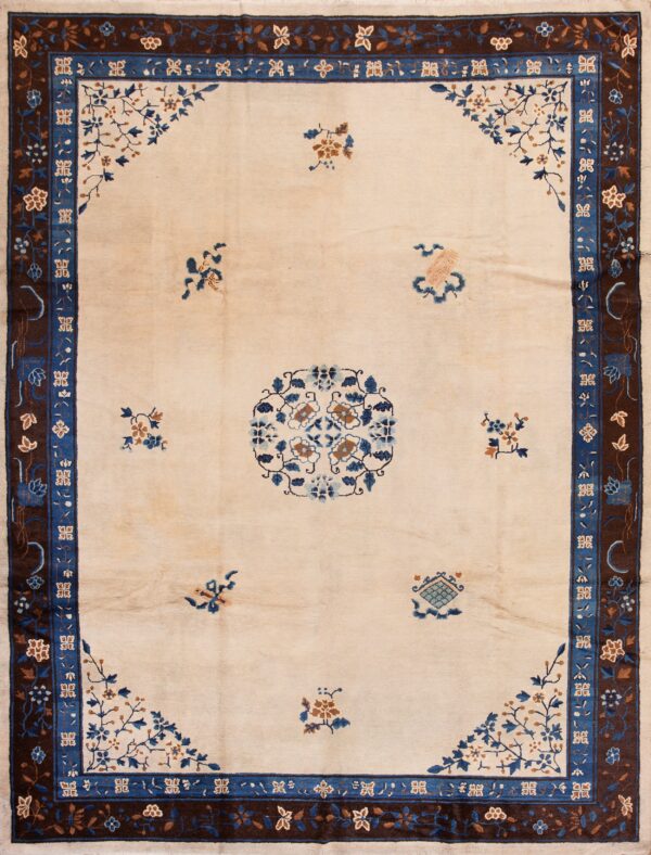 Large cream rug featuring detailed blue and brown floral borders over honey-toned wood flooring.