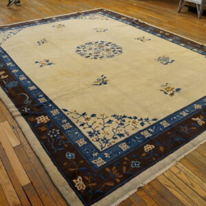 Cream area rug featuring a central medallion and broad borders in royal blue and dark brown on wood flooring.