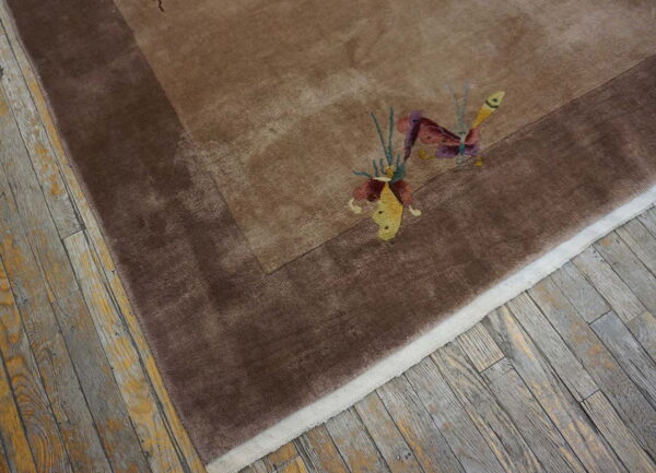 Plush brown rug with a darker border and colorful butterfly accents rests on distressed hardwood floors.