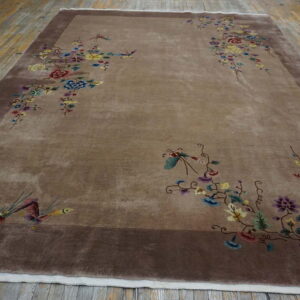 Taupe rug with dark border features scattered colorful floral and bird patterns on distressed wood.