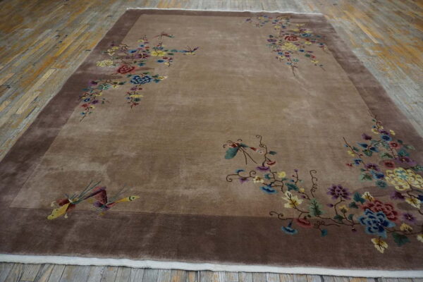 Taupe rug with dark border features scattered colorful floral and bird patterns on distressed wood.