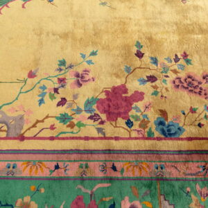 High-pile golden rug with magenta, teal, and blue florals; visible striped border in pink and green.