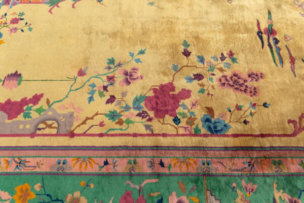 High-pile golden rug with magenta, teal, and blue florals; visible striped border in pink and green.