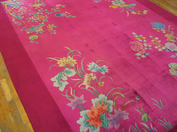 Saturated pink rug displaying multicolor botanical patterns and a darker solid border on wood floors.